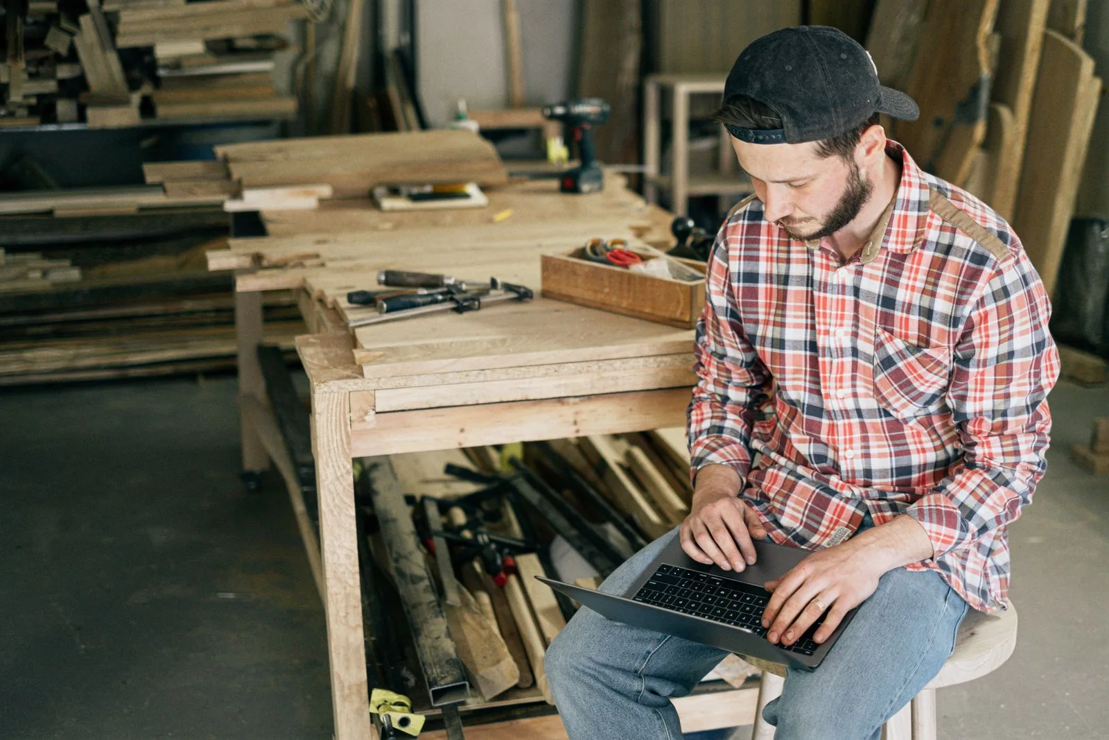 Artisan menuisier travaillant sur son ordinateur portable dans son atelier